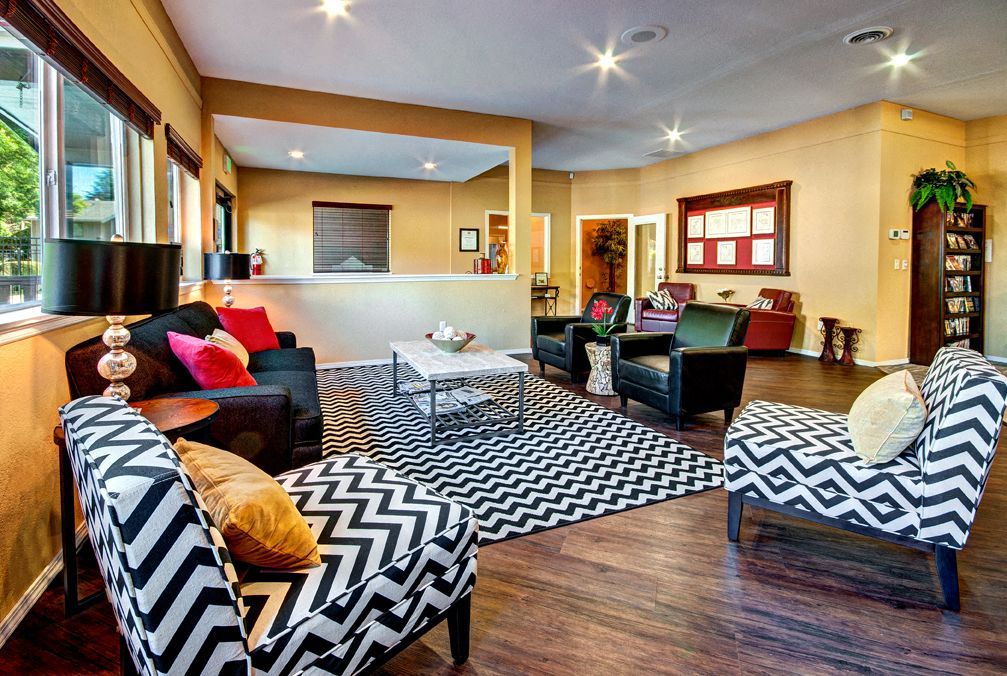 Spacious community lounge with chevron-pattern chairs, a coffee table, and a reception desk.