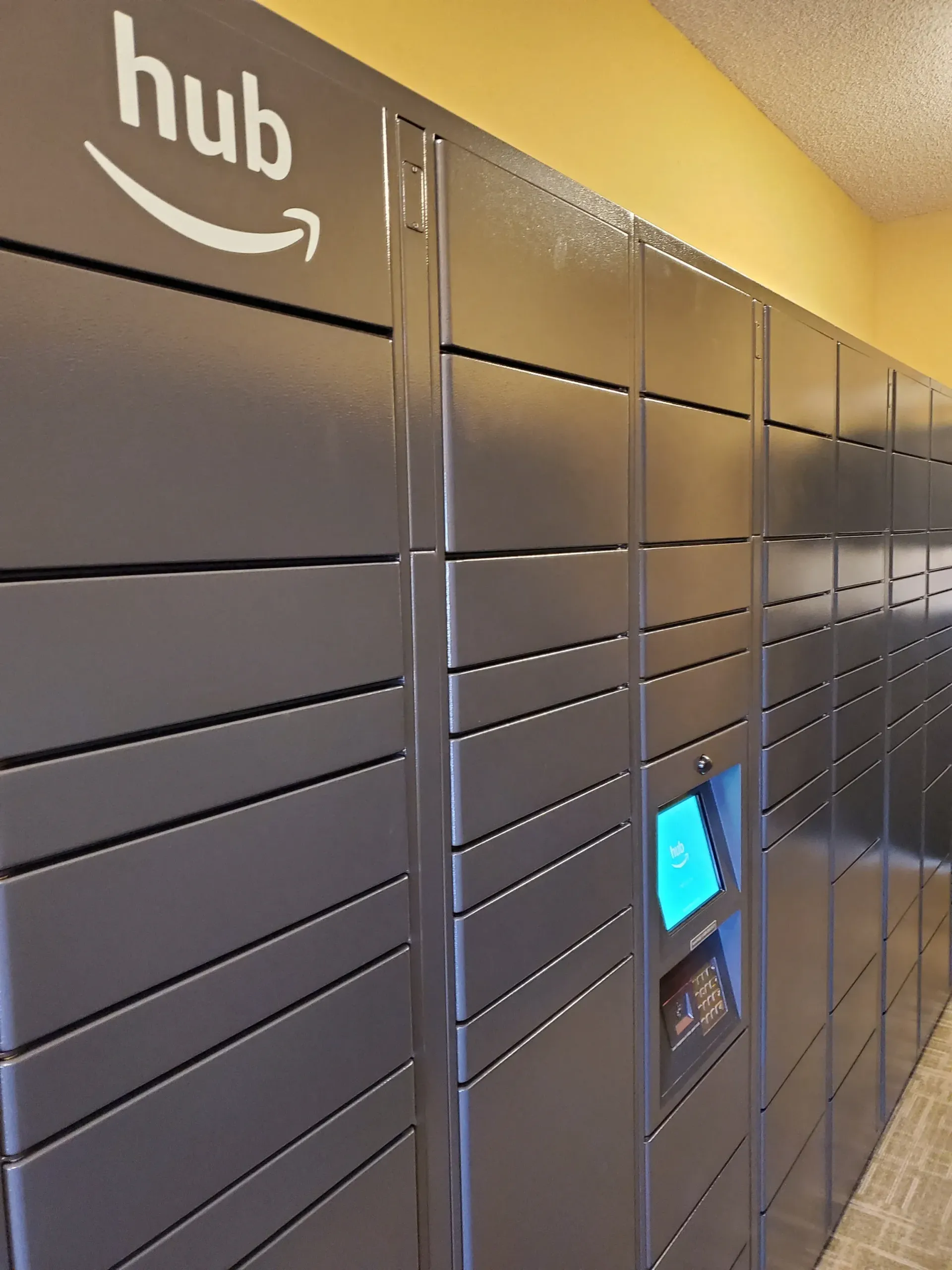 Row of grey Amazon Hub parcel lockers in a hallway.