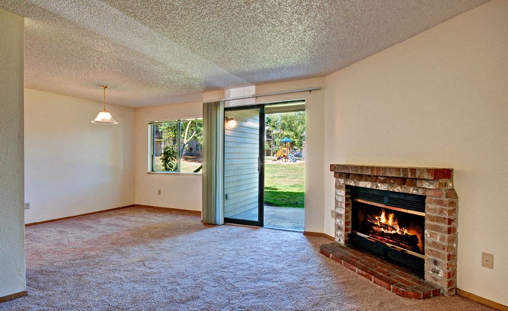 Living room with a brick fireplace, carpet, and sliding glass door to the outdoor area.