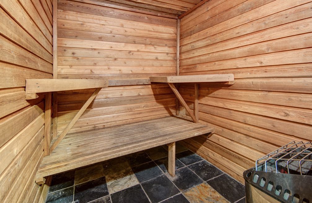 Wood-paneled sauna with benches and a heater.