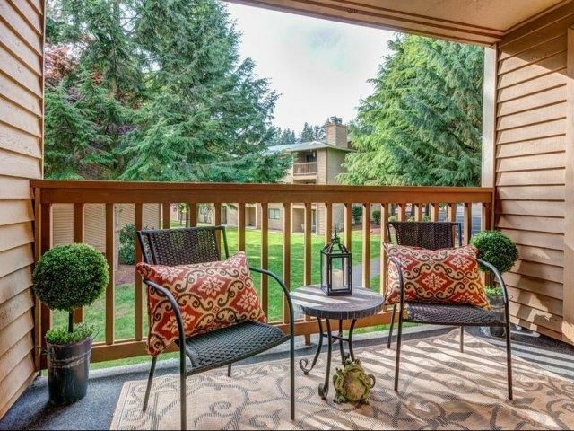 Balcony seating area with two chairs, a small table, and decorative pillows.