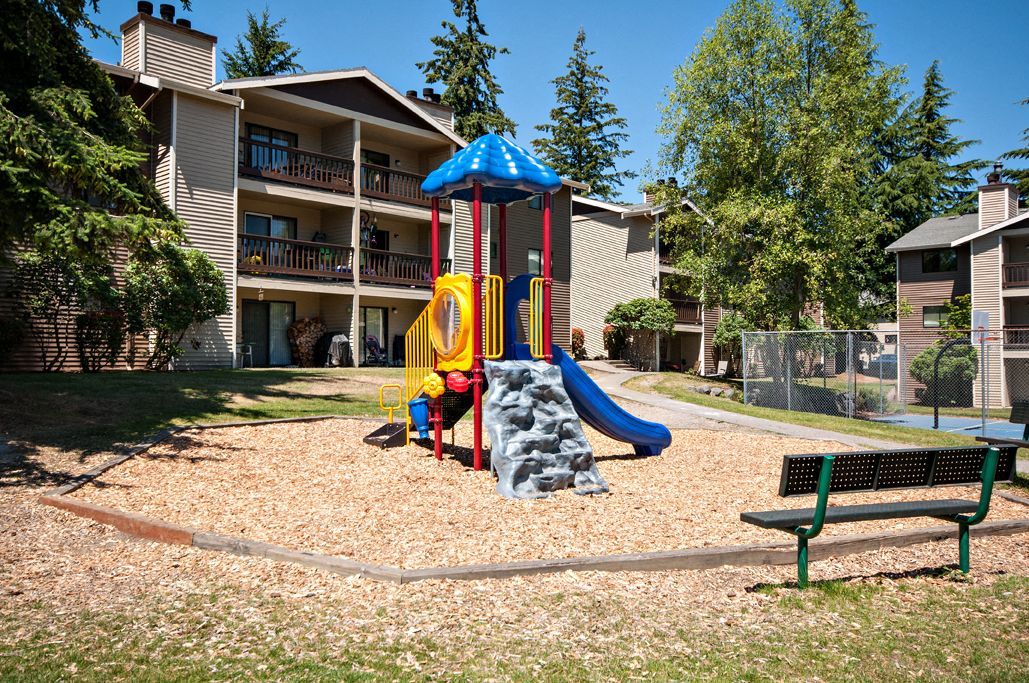 Colorful playground with slide and climbing structure in an apartment complex courtyard.