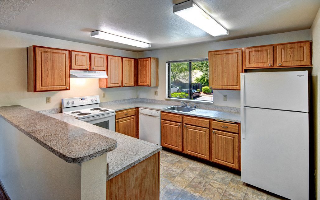 Kitchen with wooden cabinets, white appliances, and a window above the sink.