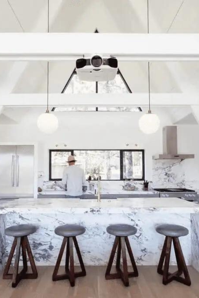 a man is standing in a kitchen with a projector hanging from the ceiling inside a vacation rental with Boss My Pad.
