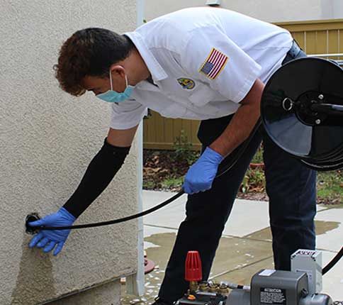 man inserting line in hole in a wall