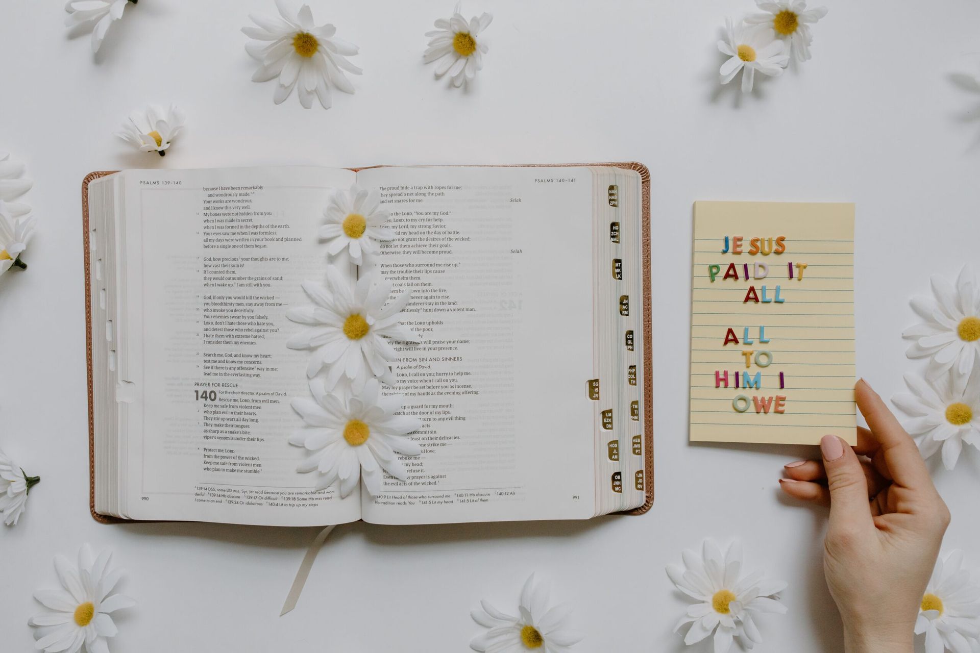 a person is holding a card that says `` jesus paid it all to him i owe '' next to a bible .