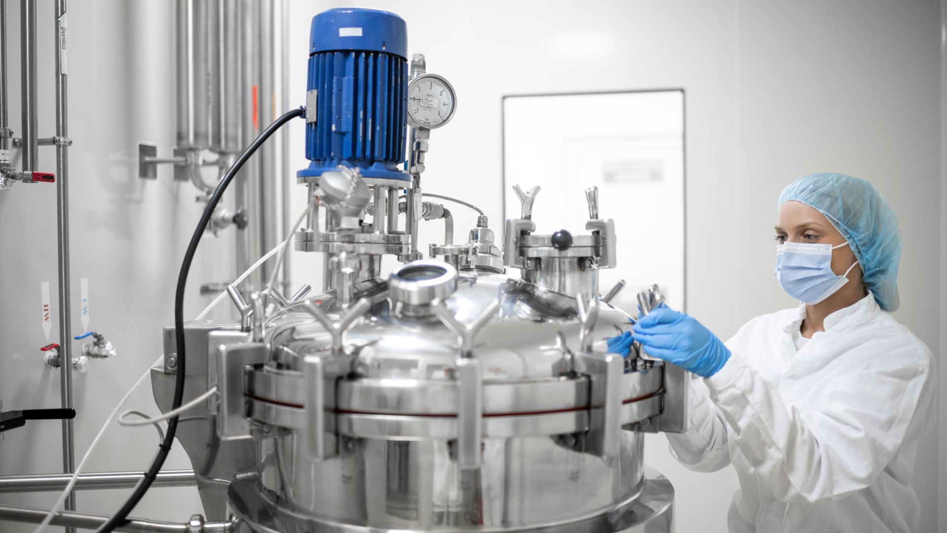 A woman wearing a mask and gloves is working on a machine.