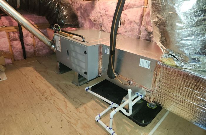 An air conditioner is sitting in the attic of a house.