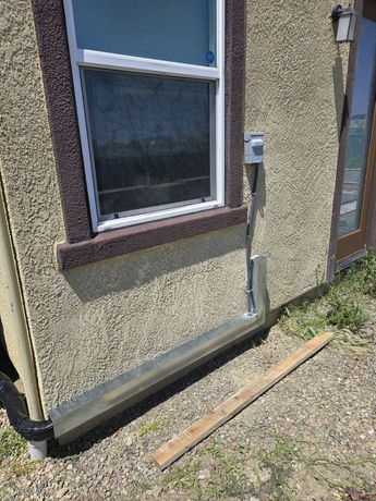 A house with a window and a drain on the side of it.
