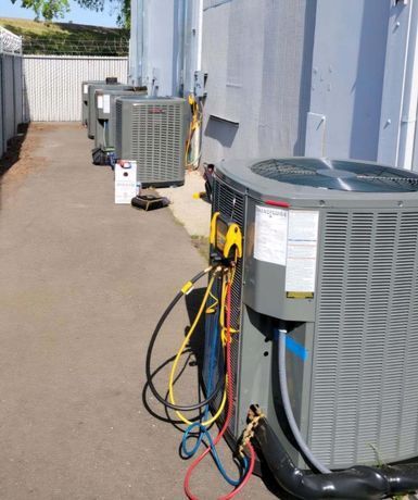 A row of air conditioners are sitting outside of a building.