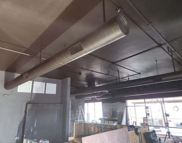 A large metal pipe is hanging from the ceiling of a building.