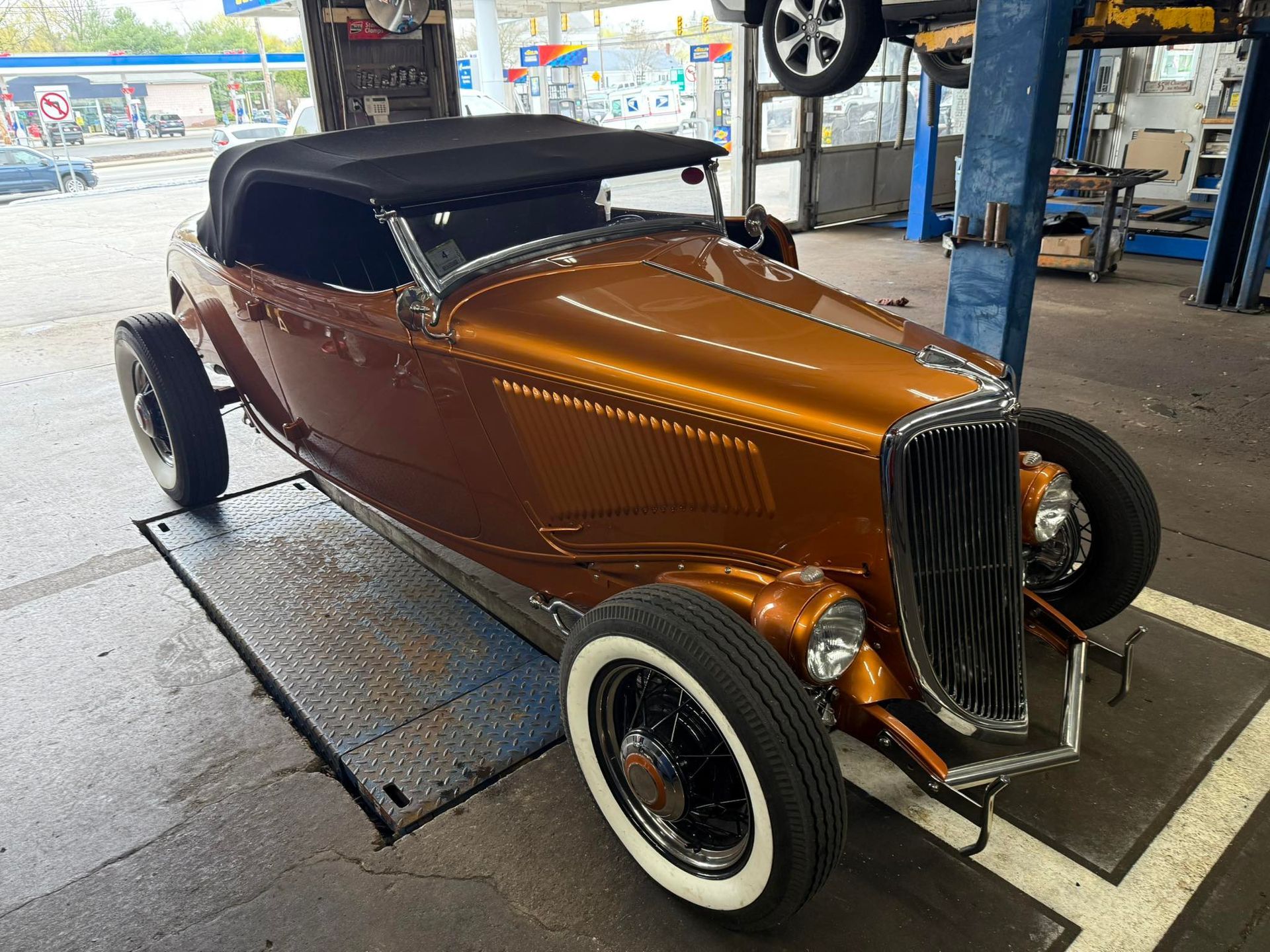 An old car is sitting on a lift in a garage.