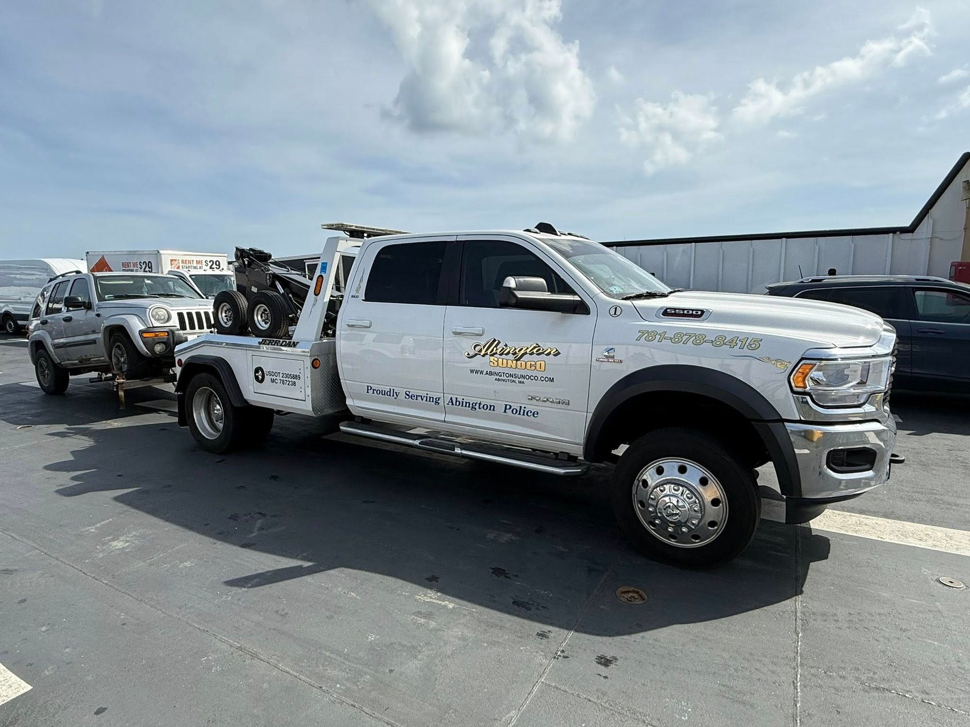 A white tow truck is parked on the side of the road.
