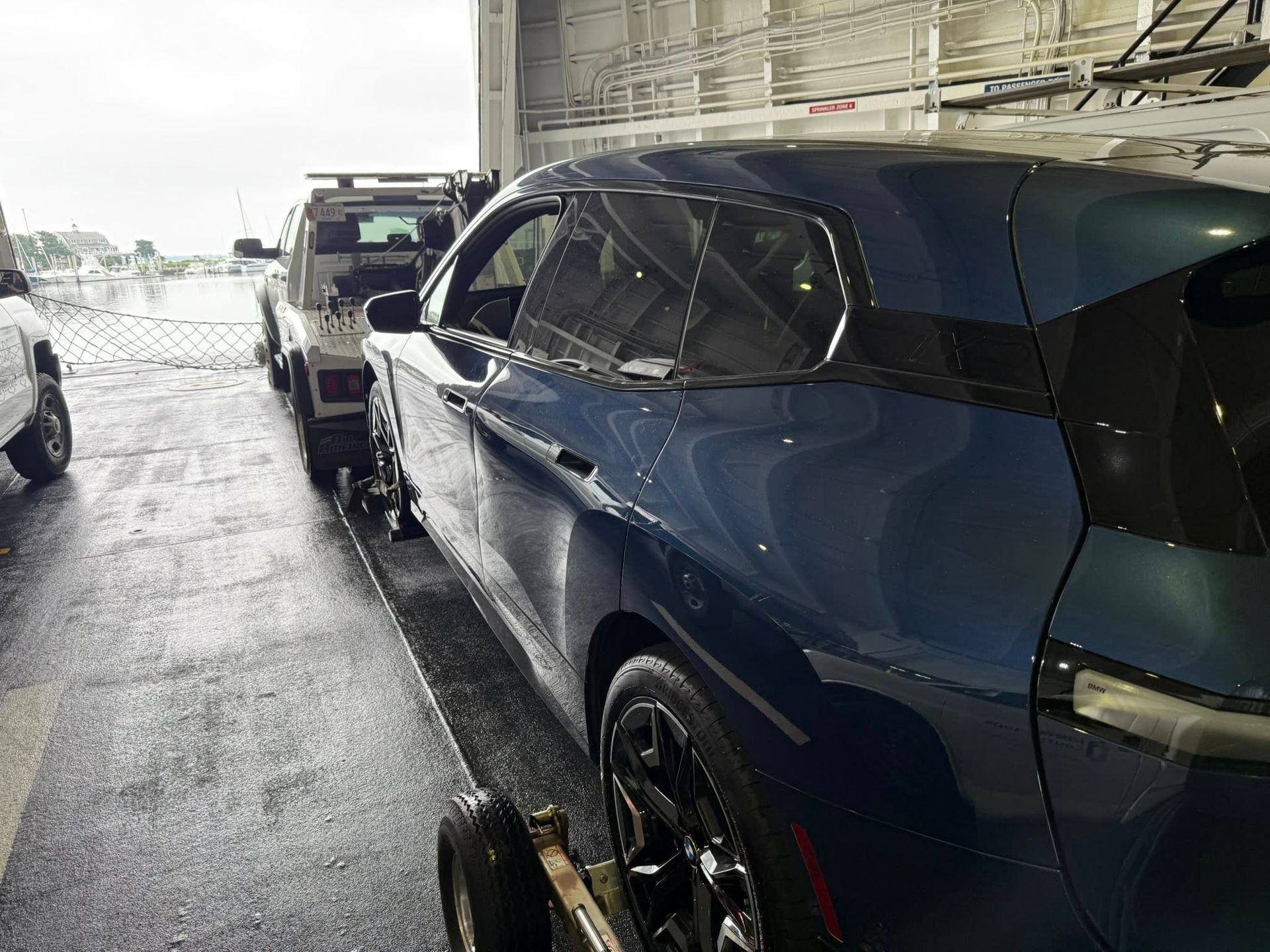 Blue car being towed inside a wet, industrial setting.