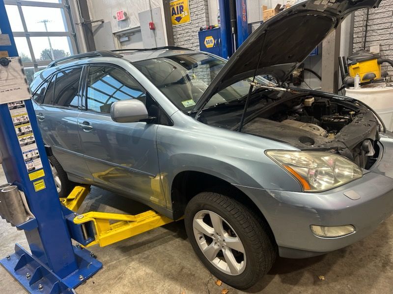 Blue SUV on a lift in a garage with the hood open, ready for repair.