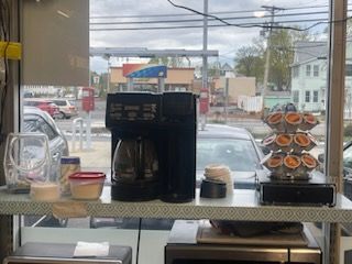 A coffee maker is sitting on a counter in front of a window.