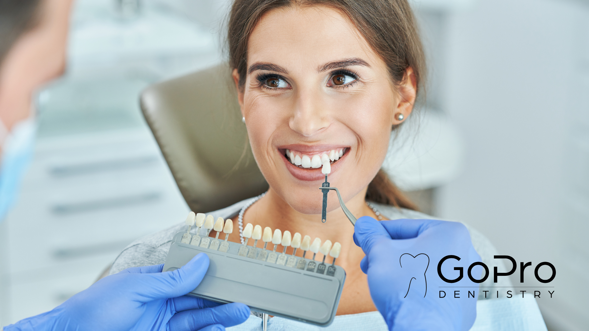 A woman is sitting in a dental chair while a dentist examines her teeth.