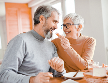 A man and a woman are sitting at a table eating food.