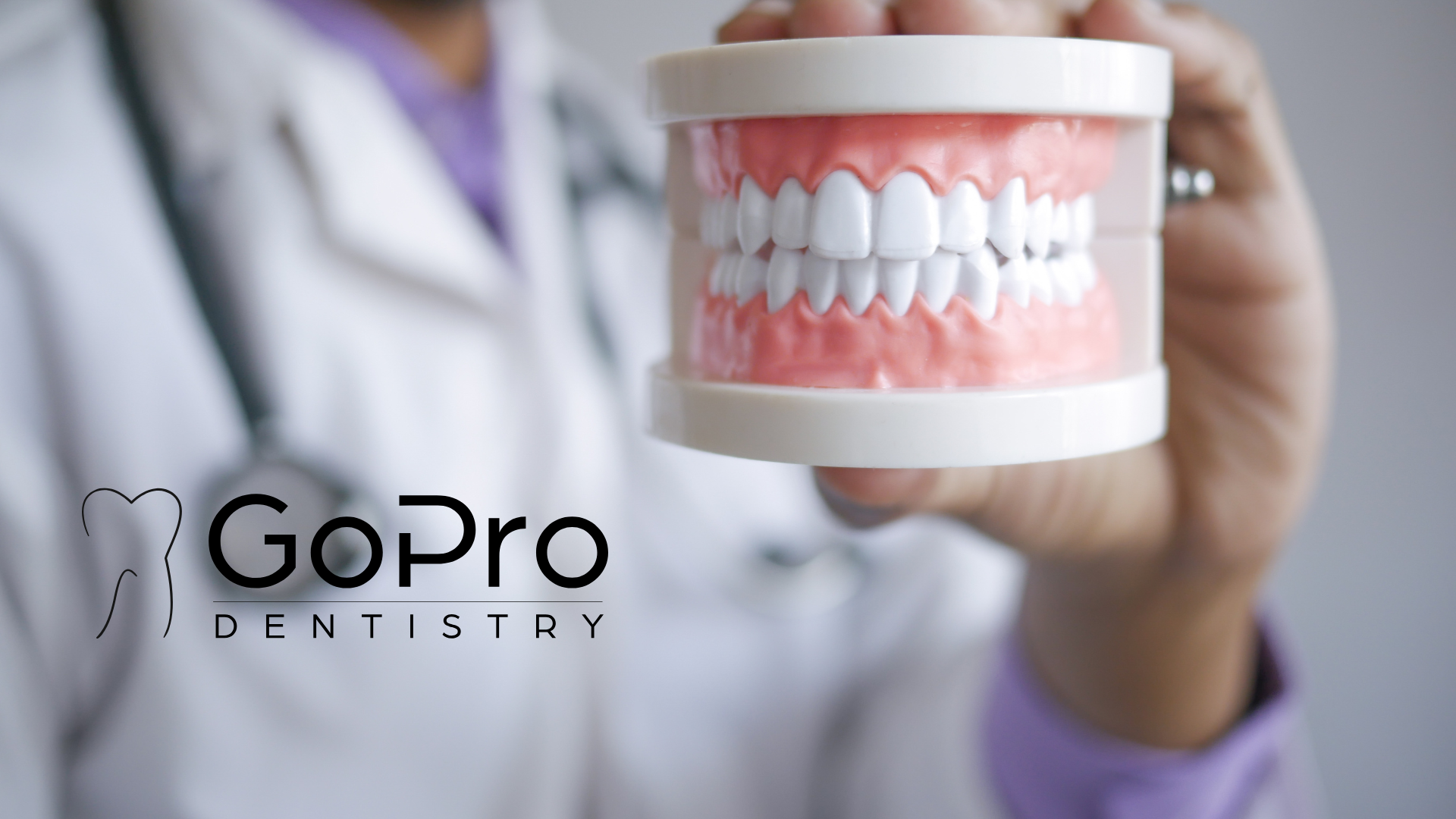 A dentist is holding a model of teeth with gopro dentistry in the background