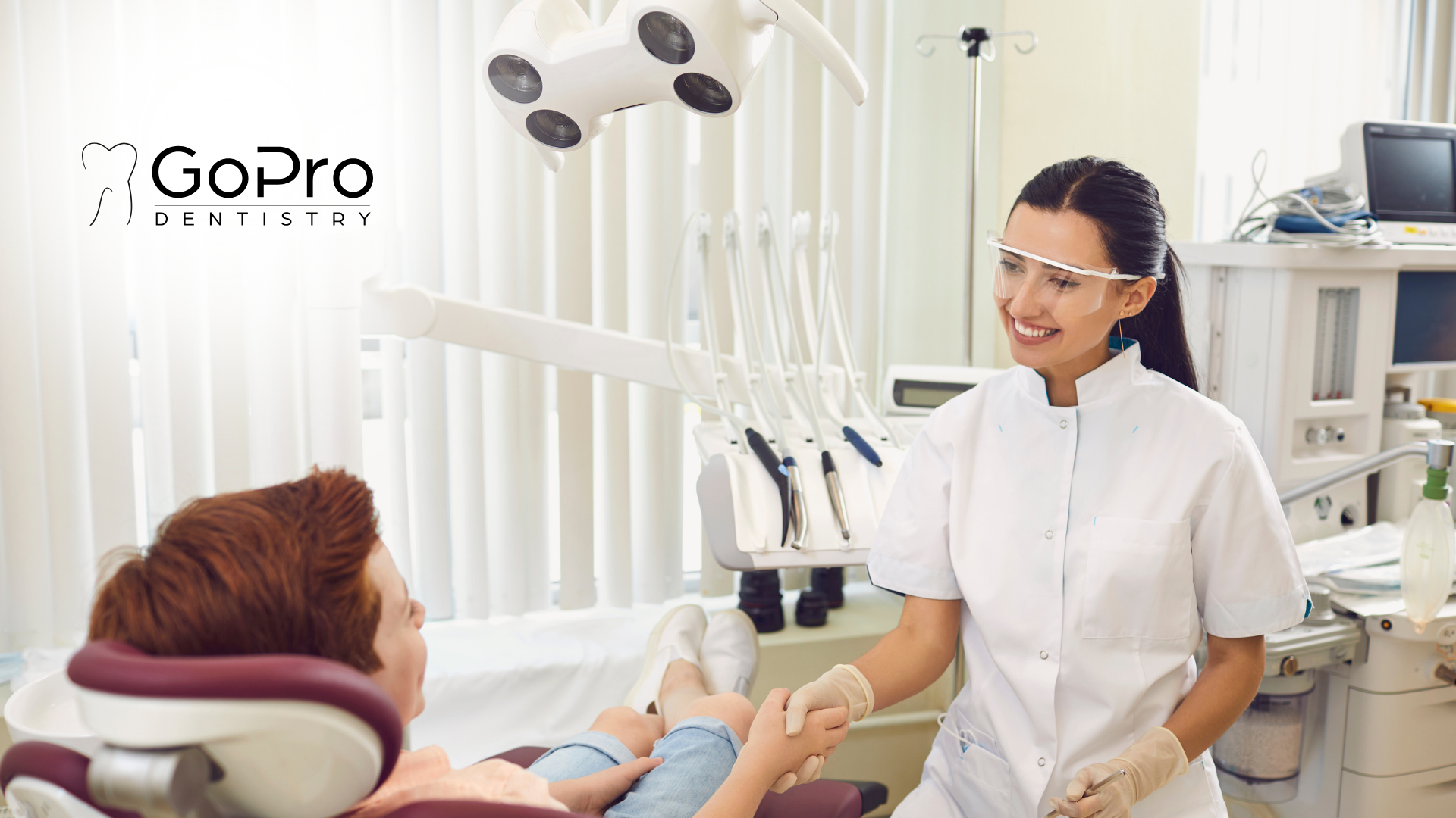 A dentist is shaking hands with a patient in a dental chair.