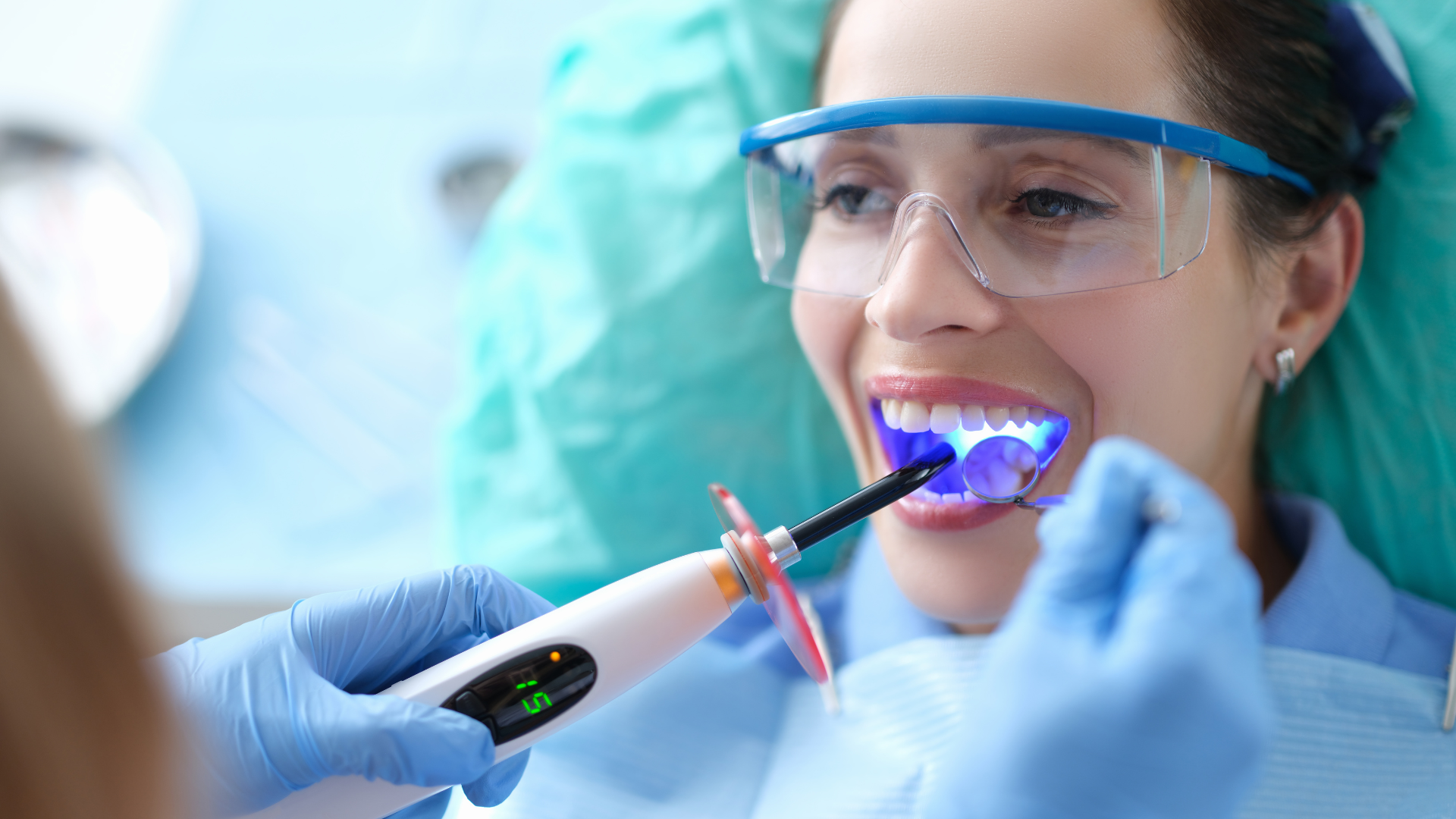 A woman is getting her teeth whitened by a dentist.