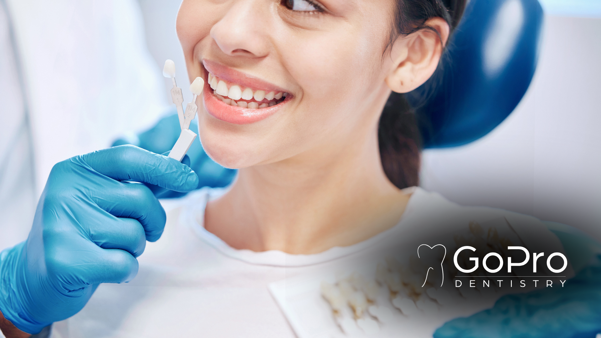 A woman is sitting in a dental chair while a dentist examines her teeth.