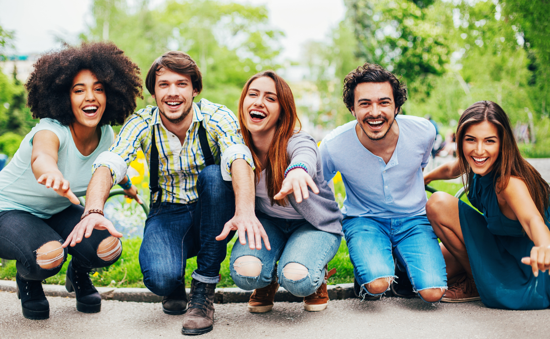 A group of young people are posing for a picture in a park.