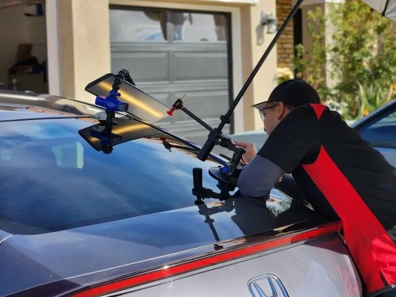 Dark red sports car with sleek design, reflected on a dark surface.