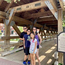 Family of four on a wooden bridge, posing for a photo.