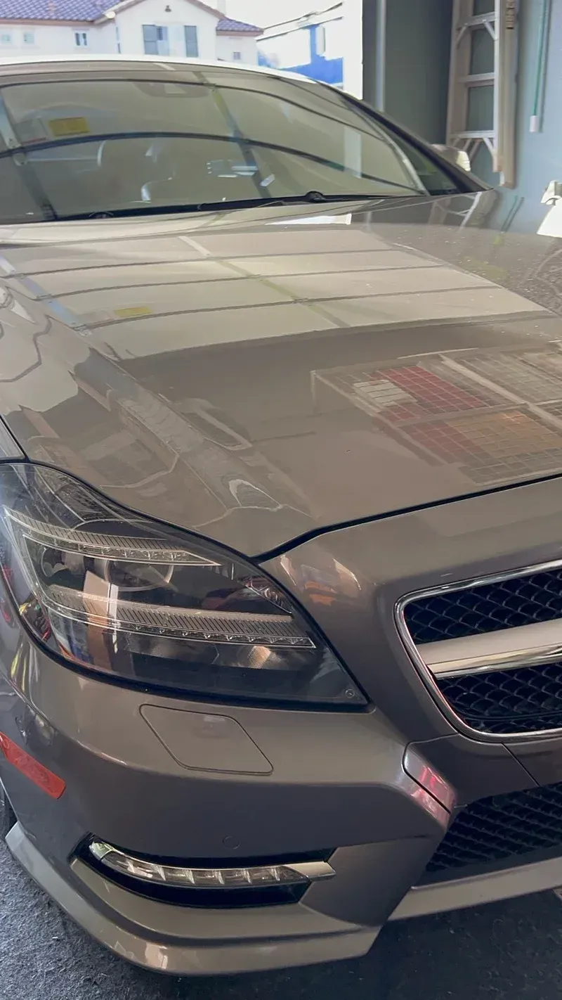 Gray Mercedes-Benz sedan in a garage, focusing on the front, including headlights and grille.