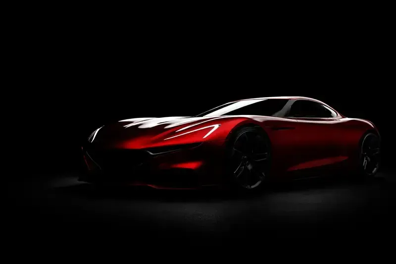 Red sports car in a darkened studio setting, illuminated to highlight its sleek design.