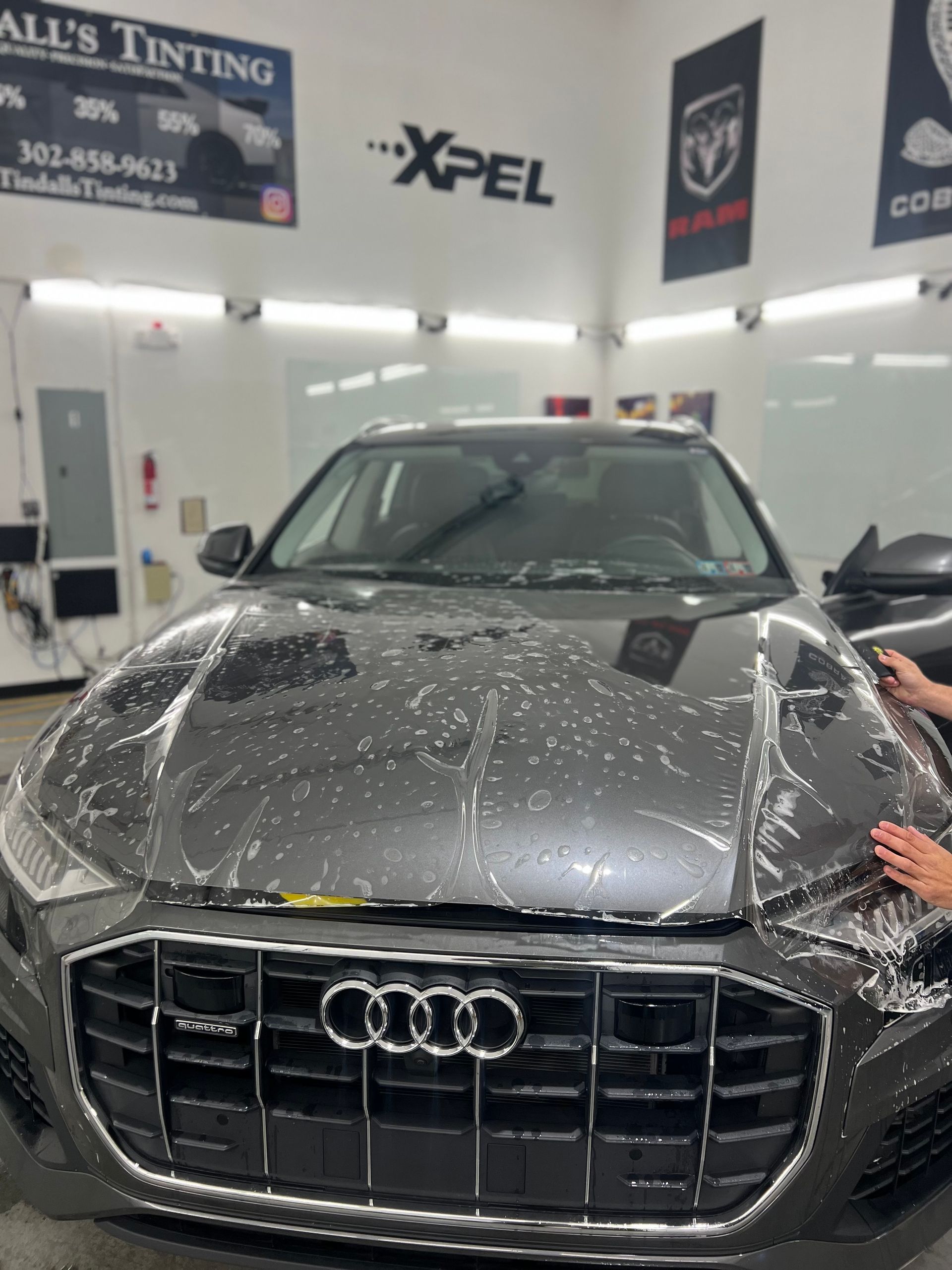 A person is applying a protective film to an audi car