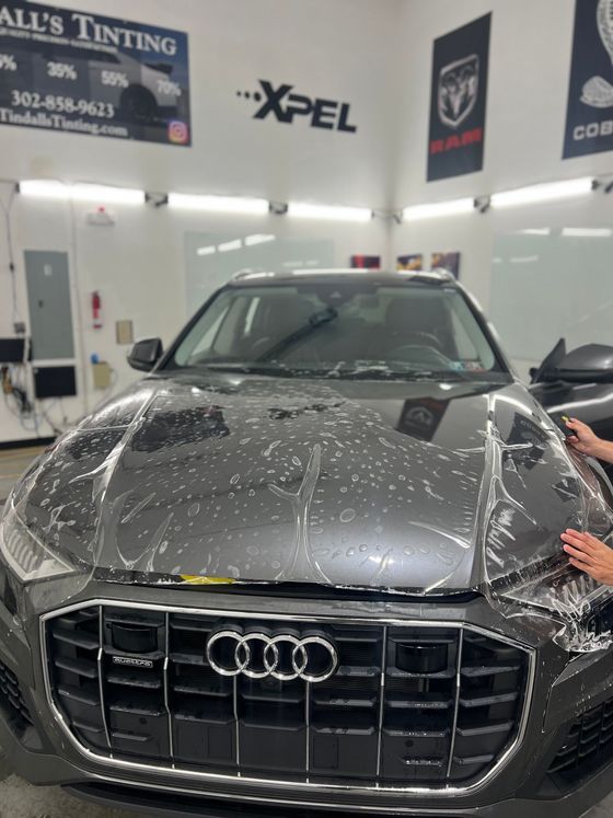 A person is applying a protective film to an audi car