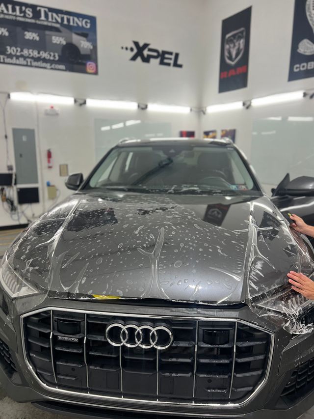 A person is applying a protective film to an audi car