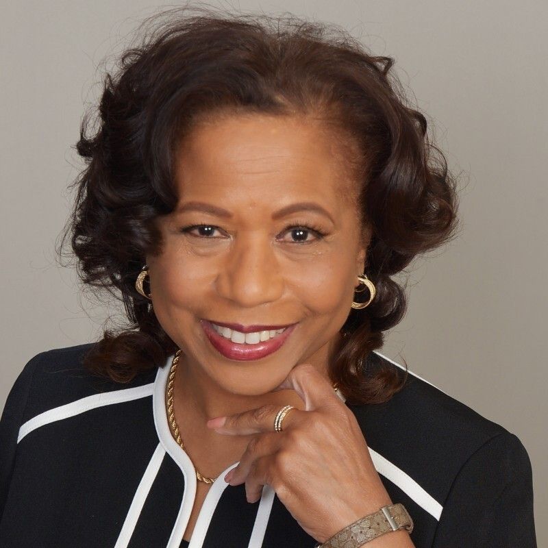 A woman wearing earrings and a watch smiles for the camera