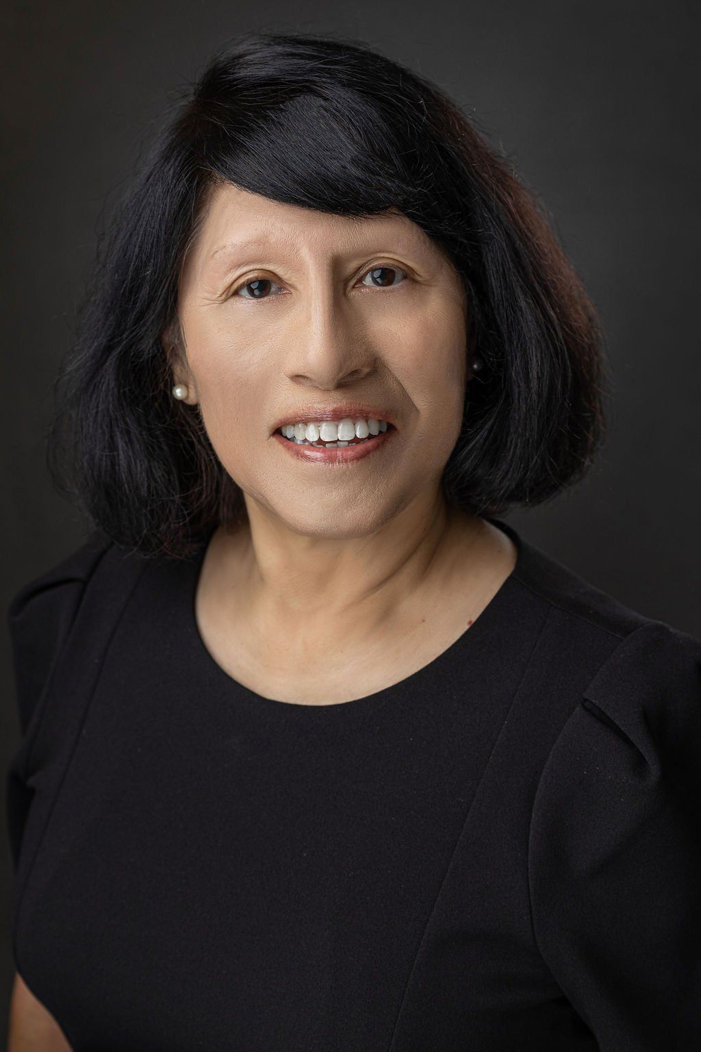 A woman in a black dress is smiling for the camera.