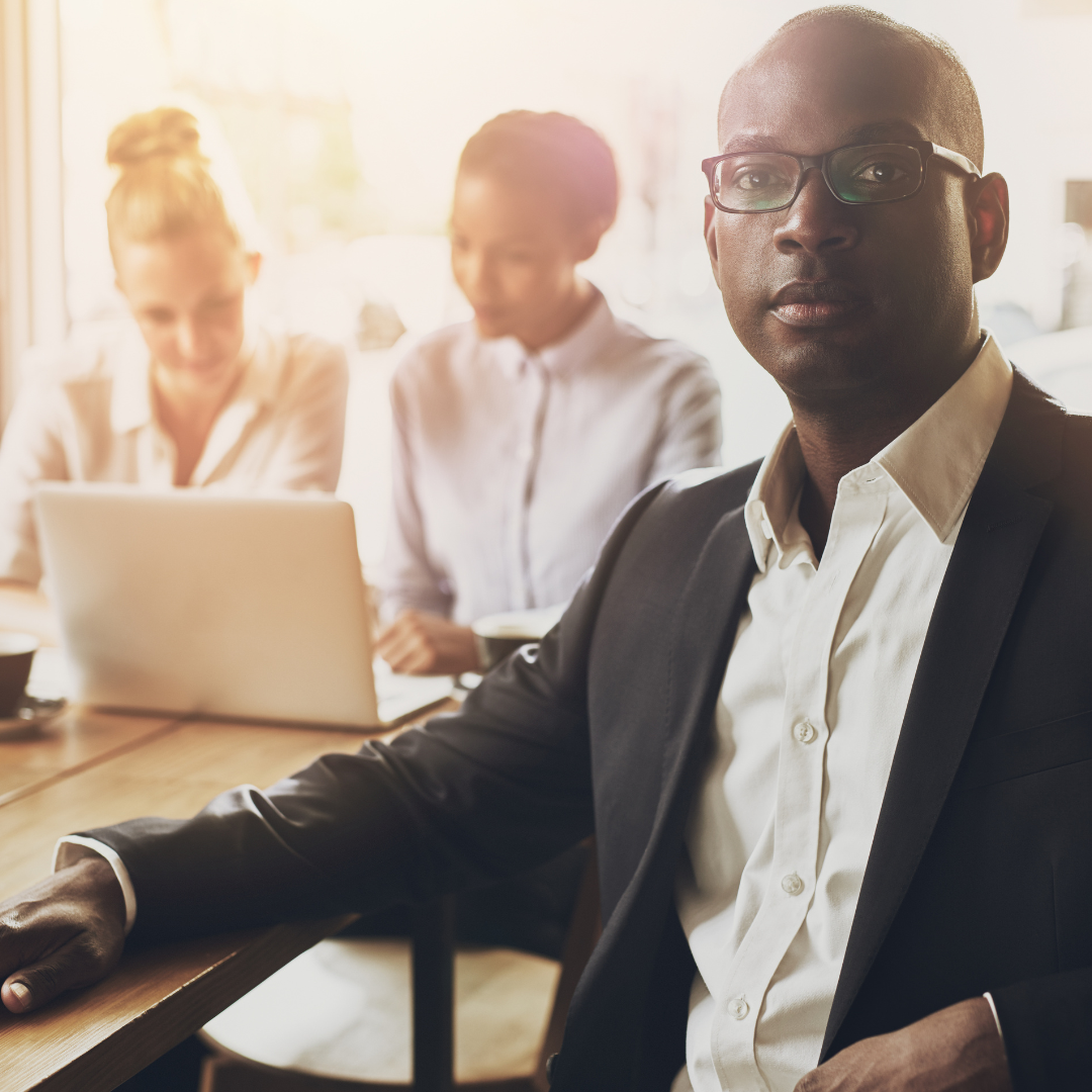 A man in a suit is sitting at a table with a laptop