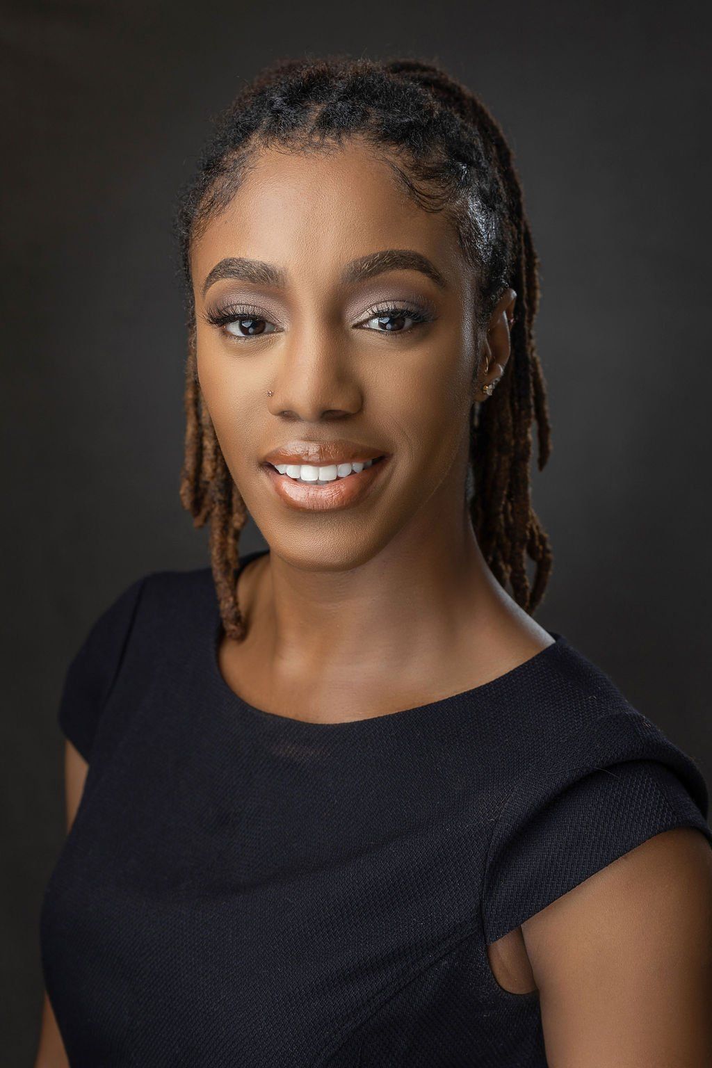 A woman with dreadlocks is smiling for the camera while wearing a black shirt.