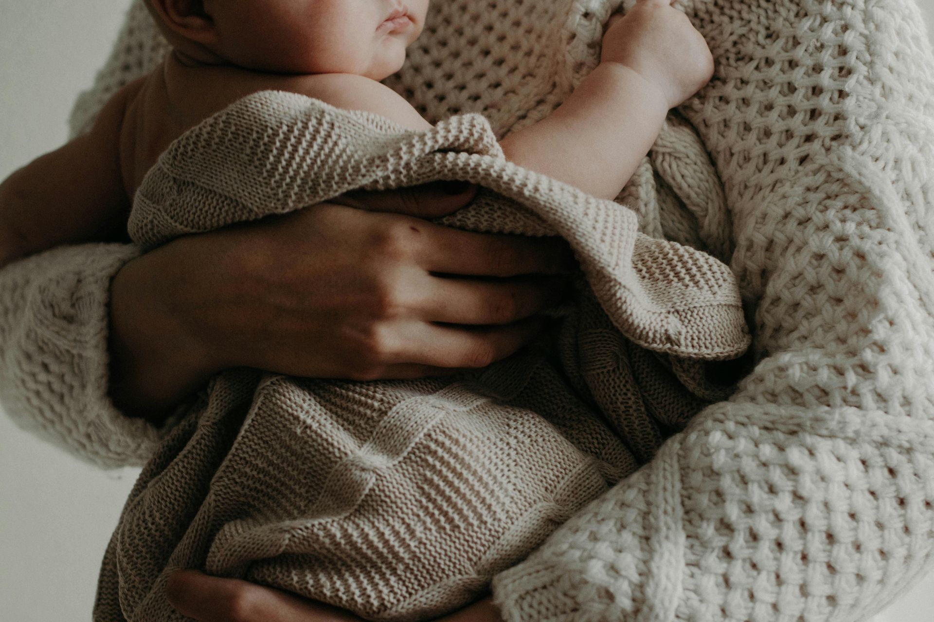 A woman is holding a baby wrapped in a blanket.