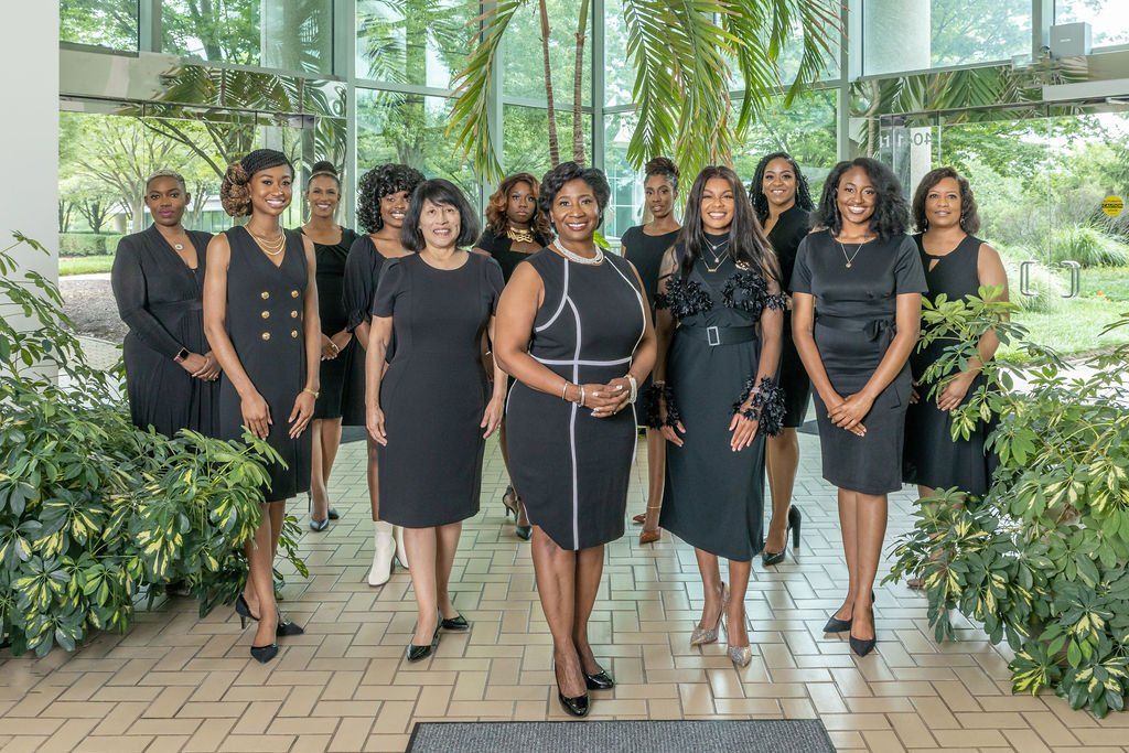 A group of women in black dresses are posing for a picture.