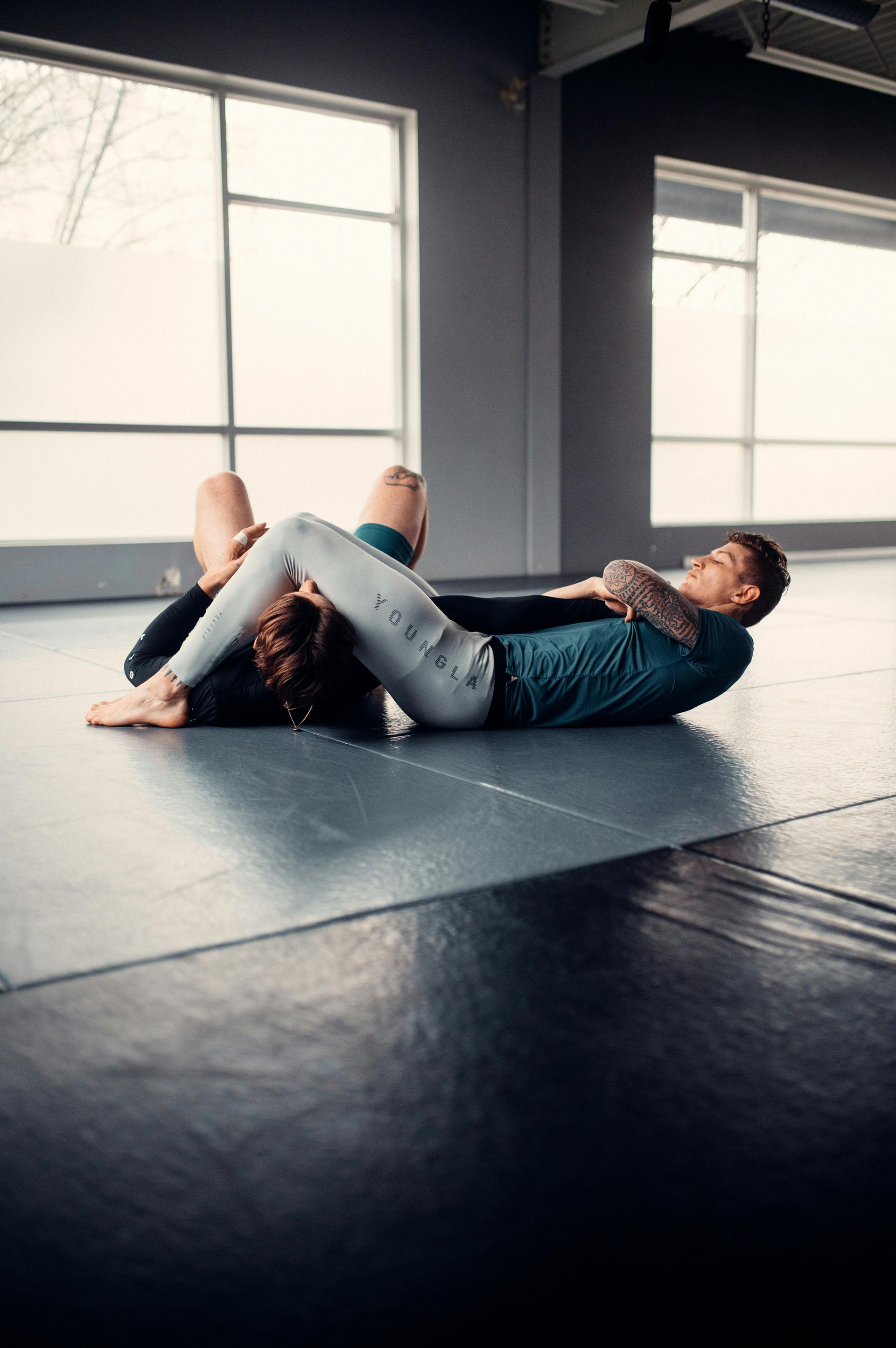 Two men are wrestling on a blue mat in a gym