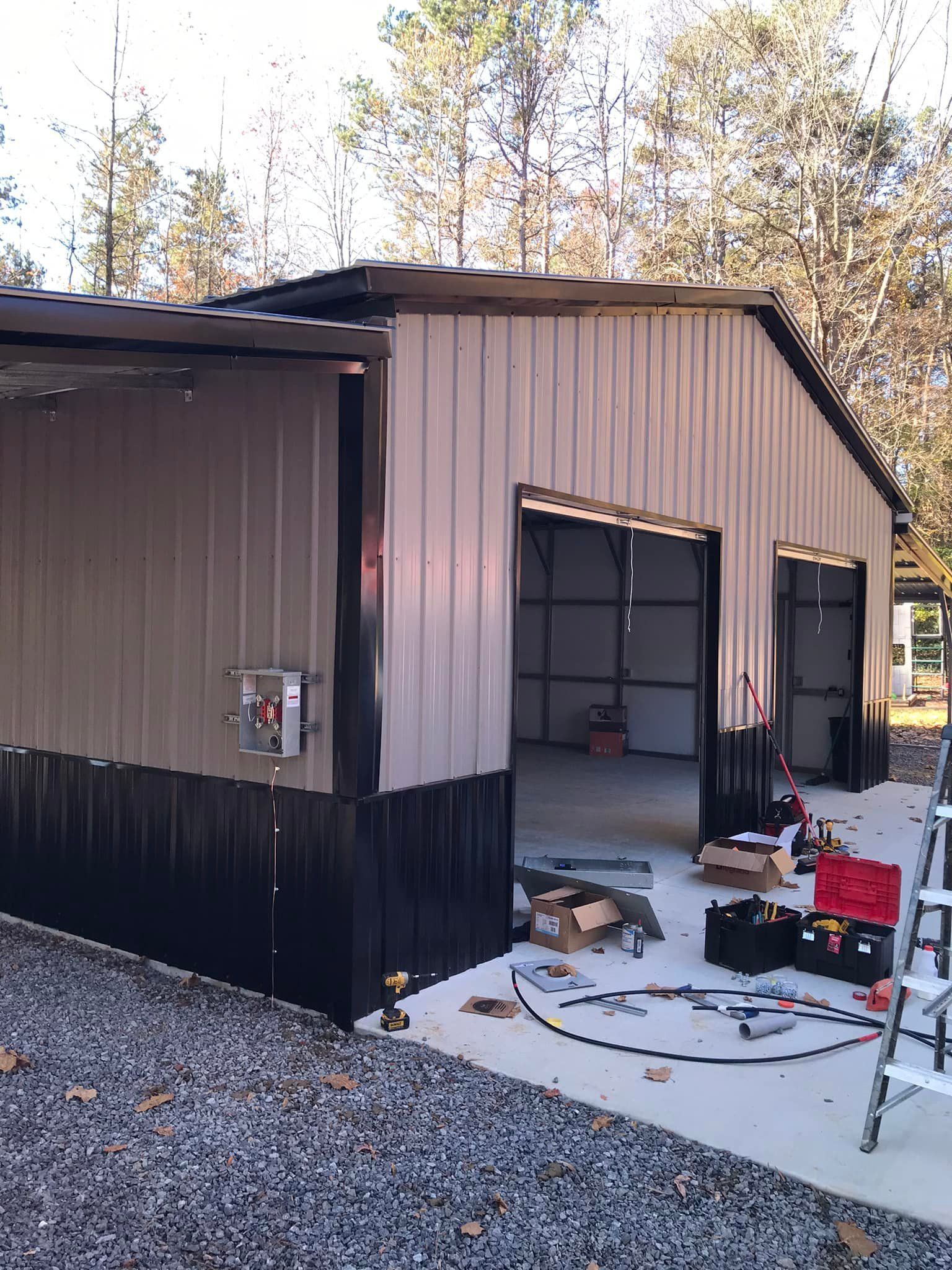 A metal garage is being built with a ladder in front of it.