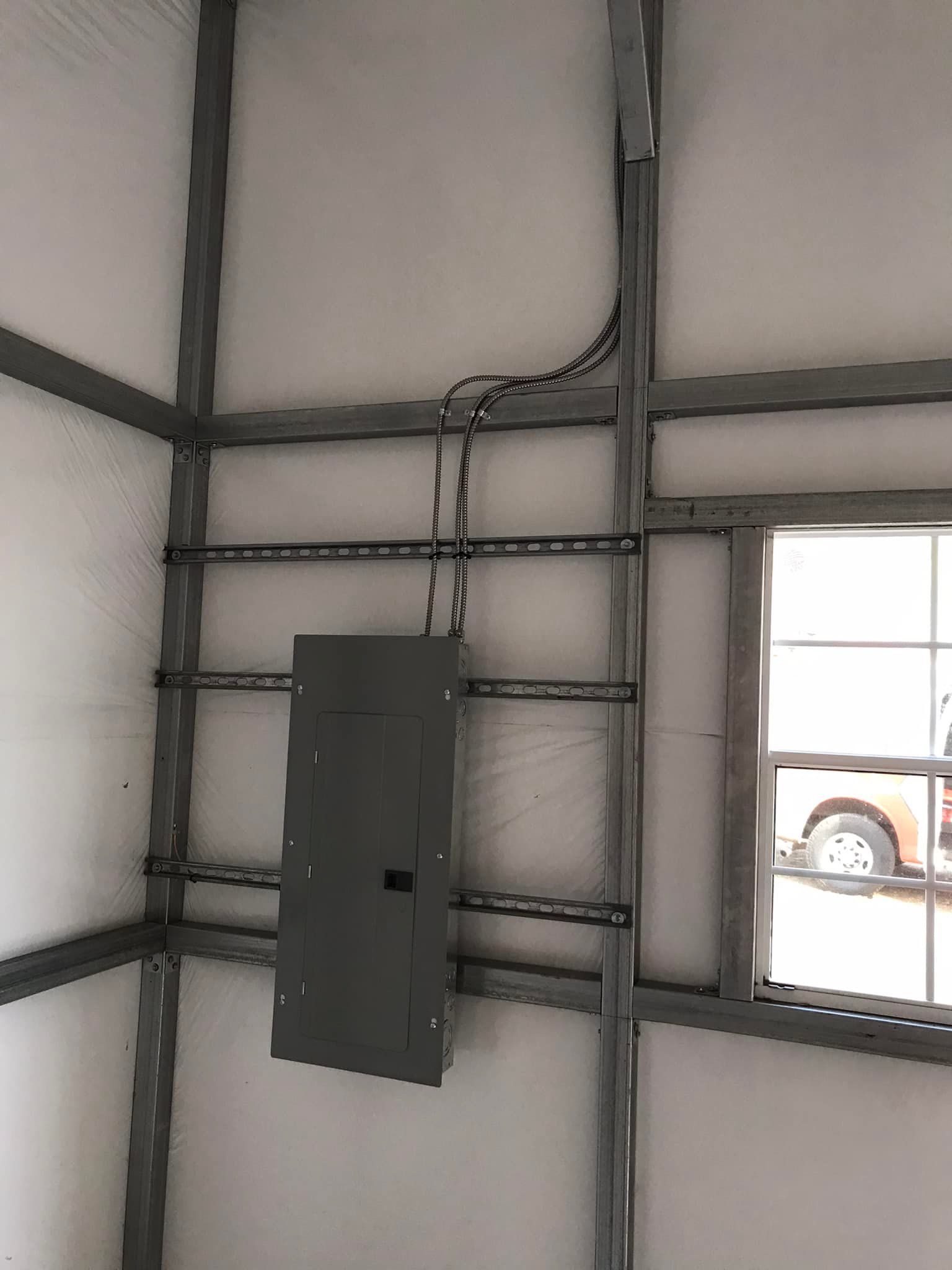 A electrical box is hanging on a wall next to a window.