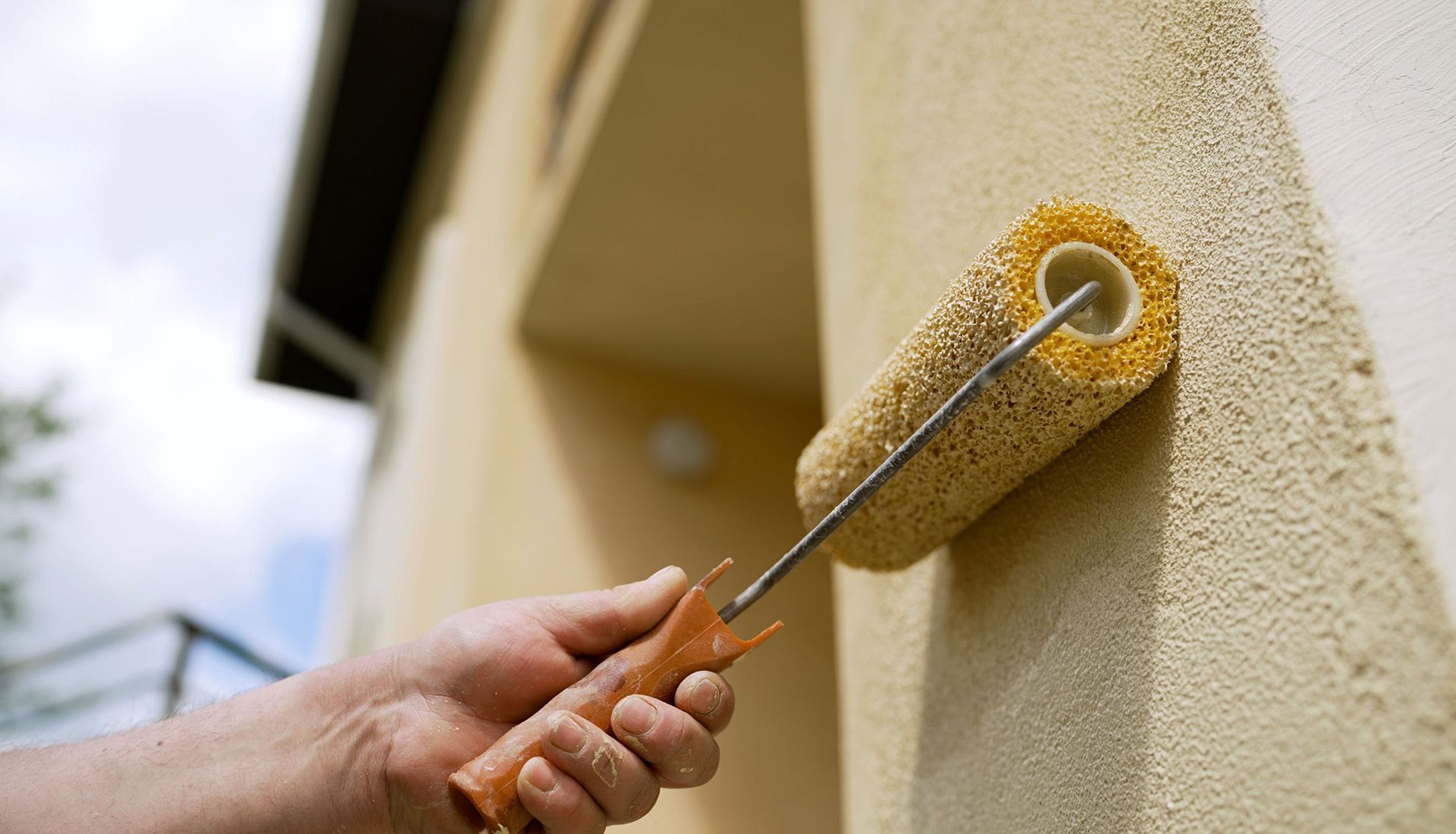 A person is painting a wall with a paint roller.