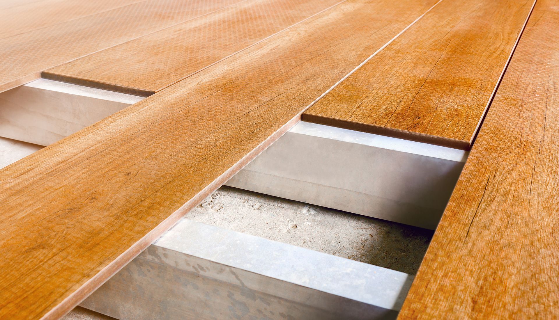 A close up of a wooden floor with a concrete foundation.