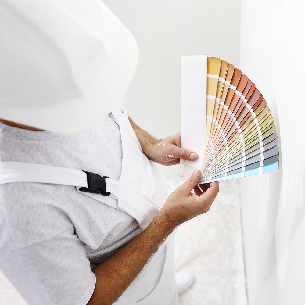 A man wearing a hard hat is holding a color palette