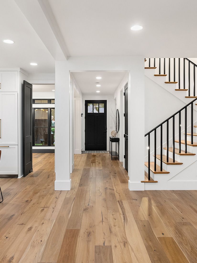 A hallway with hardwood floors and stairs in a house.