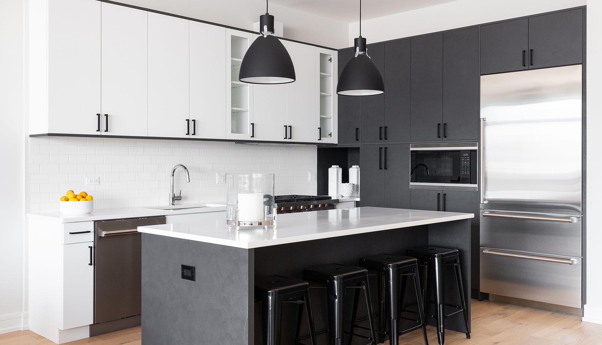 A kitchen with black cabinets and stools and a large island.