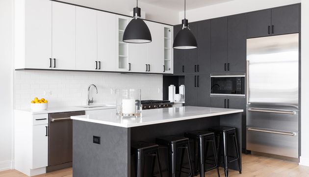 A kitchen with black cabinets and stools and a large island.