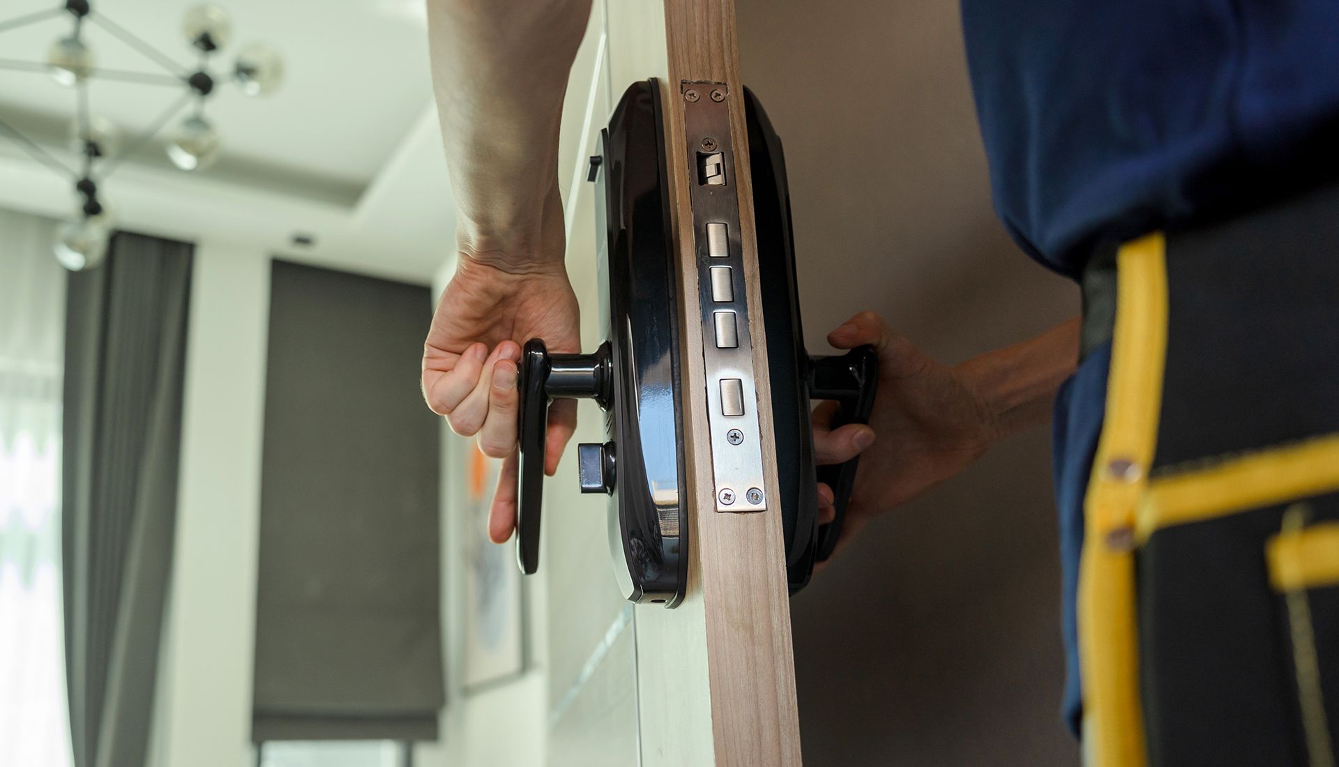A man is installing a smart door lock on a wooden door.
